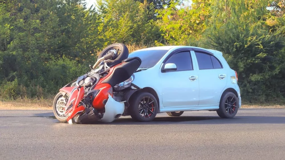 Collision between a motorcycle and a car resulting in damage to both vehicles in Miami, FL.