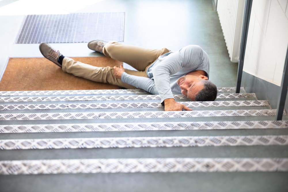Middle-aged man resting on staircase after a dangerous slip and fall incident in Miami, FL