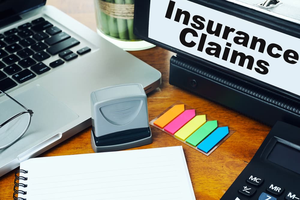 Concept of insurance claims with ring binder and office supplies on a desktop, blurred background.