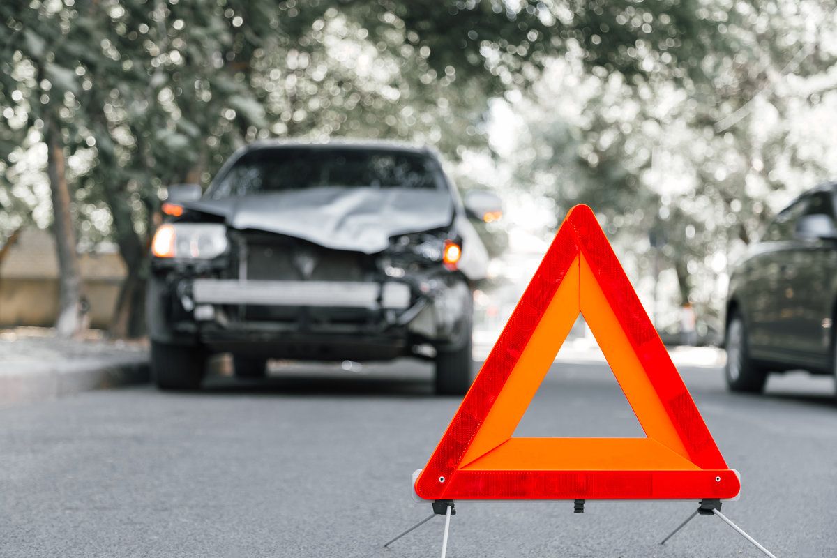 Red emergency stop triangle sign on road in car accident scene. Broken SUV car on road at traffic accident. Car crash traffic accident on city road after collision