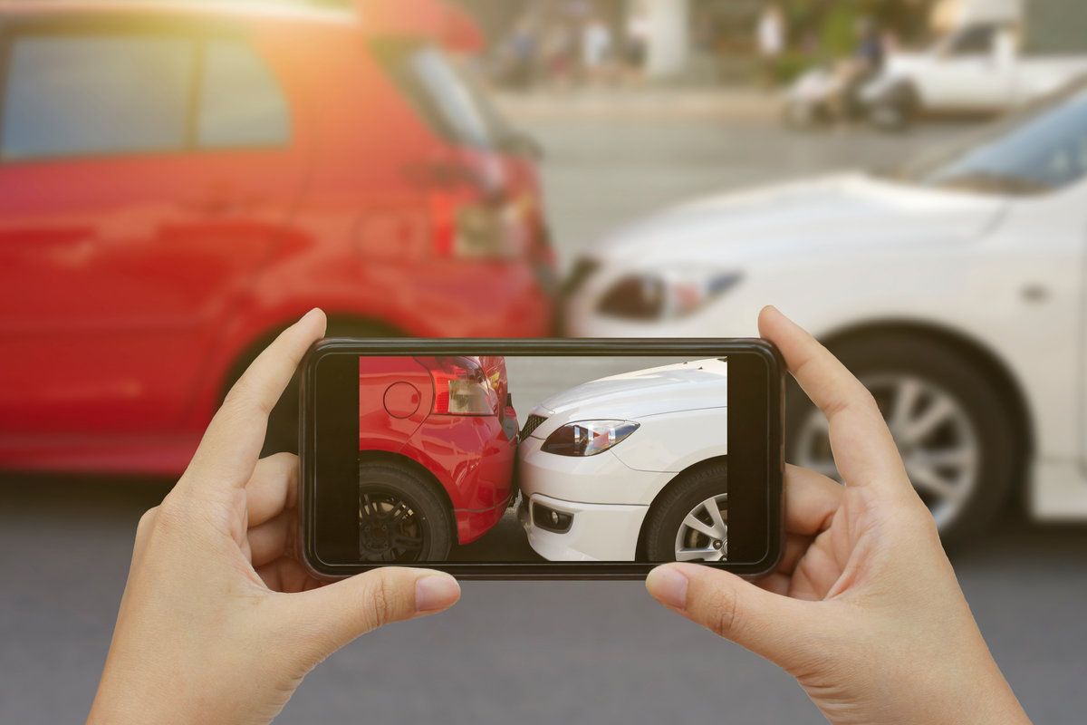 Close up hand holding smartphone and take photo at The scene of a car crash and accident, car accident for car insuranc claim
